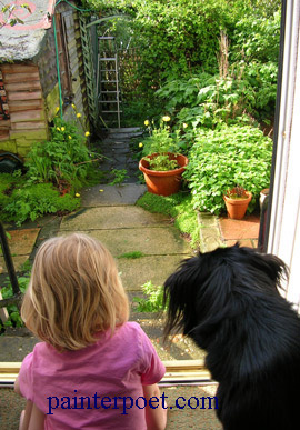 a child and a dog sitting on the floor by the back steps looking at the damp garden.